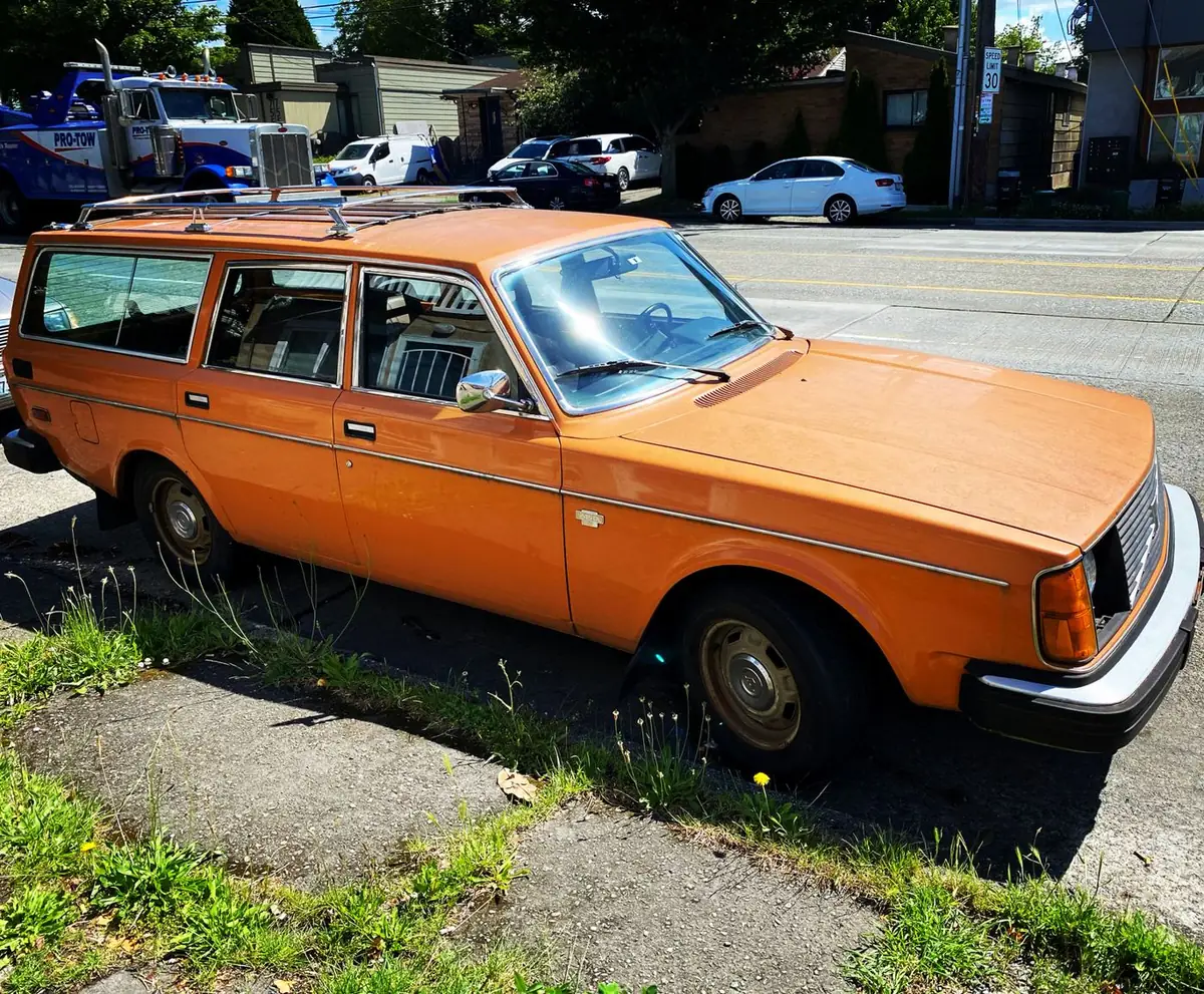 An orange Volvo 245 wagon with a chrome roof rack